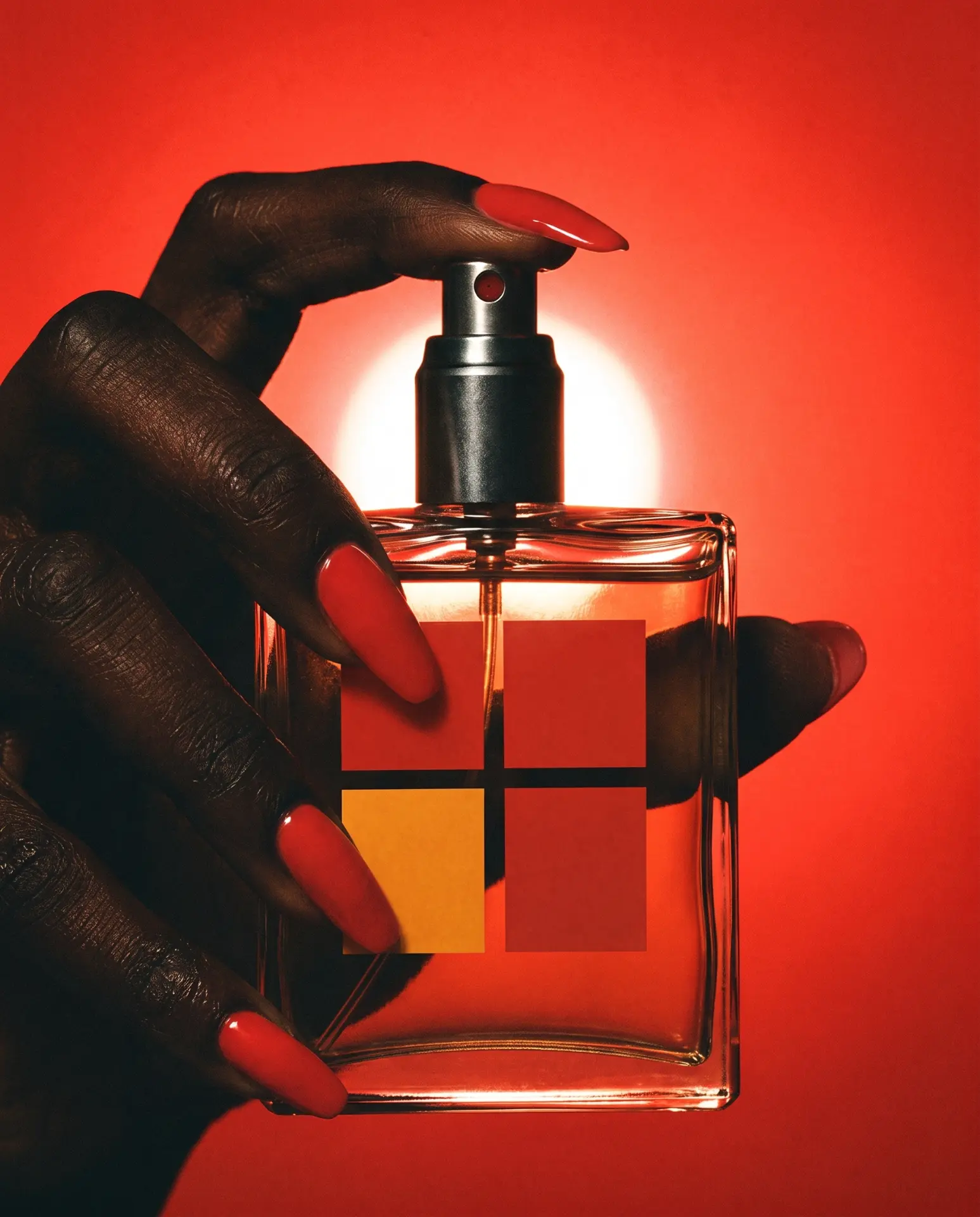 Hand with long red nails pressing a clear fragrance bottle against a glowing red backdrop